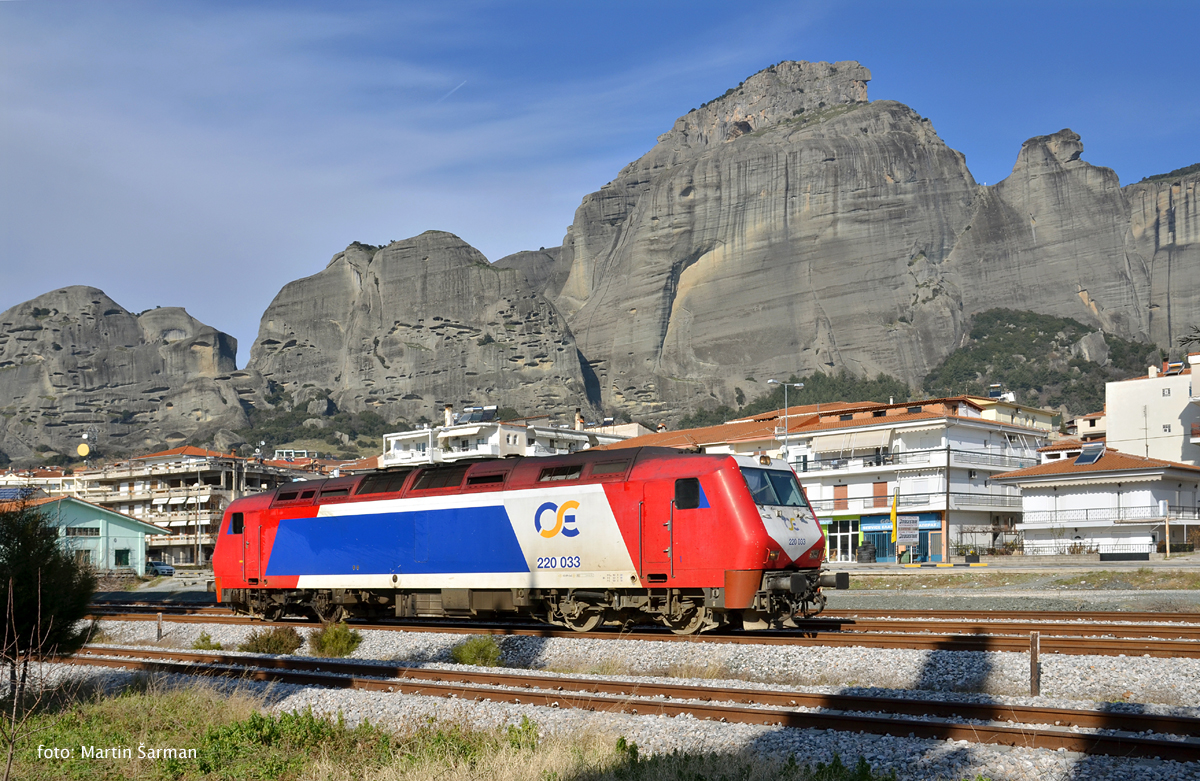 Od vlaku IC 884 (Atény-Kalambaka) odstupuje po 300 km jízdy lokomotiva 220.033, aby večer mohla opět odvézt vlak IC 885 do Atén. Na pozadí se vyjímají slepencové skaly, v nichž se nachází proslulé kláštery Meteora.