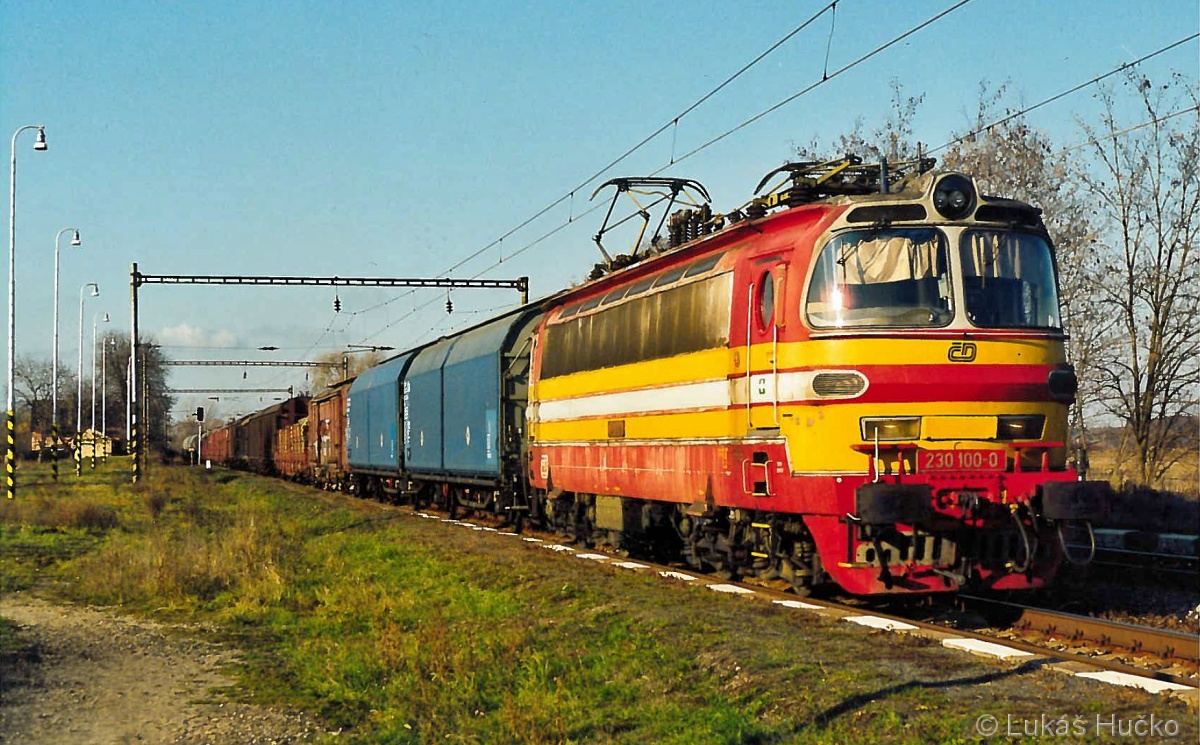 Stroj 230.100 s nákladním vlakem projíždí zastávkou dne 08.11.2003